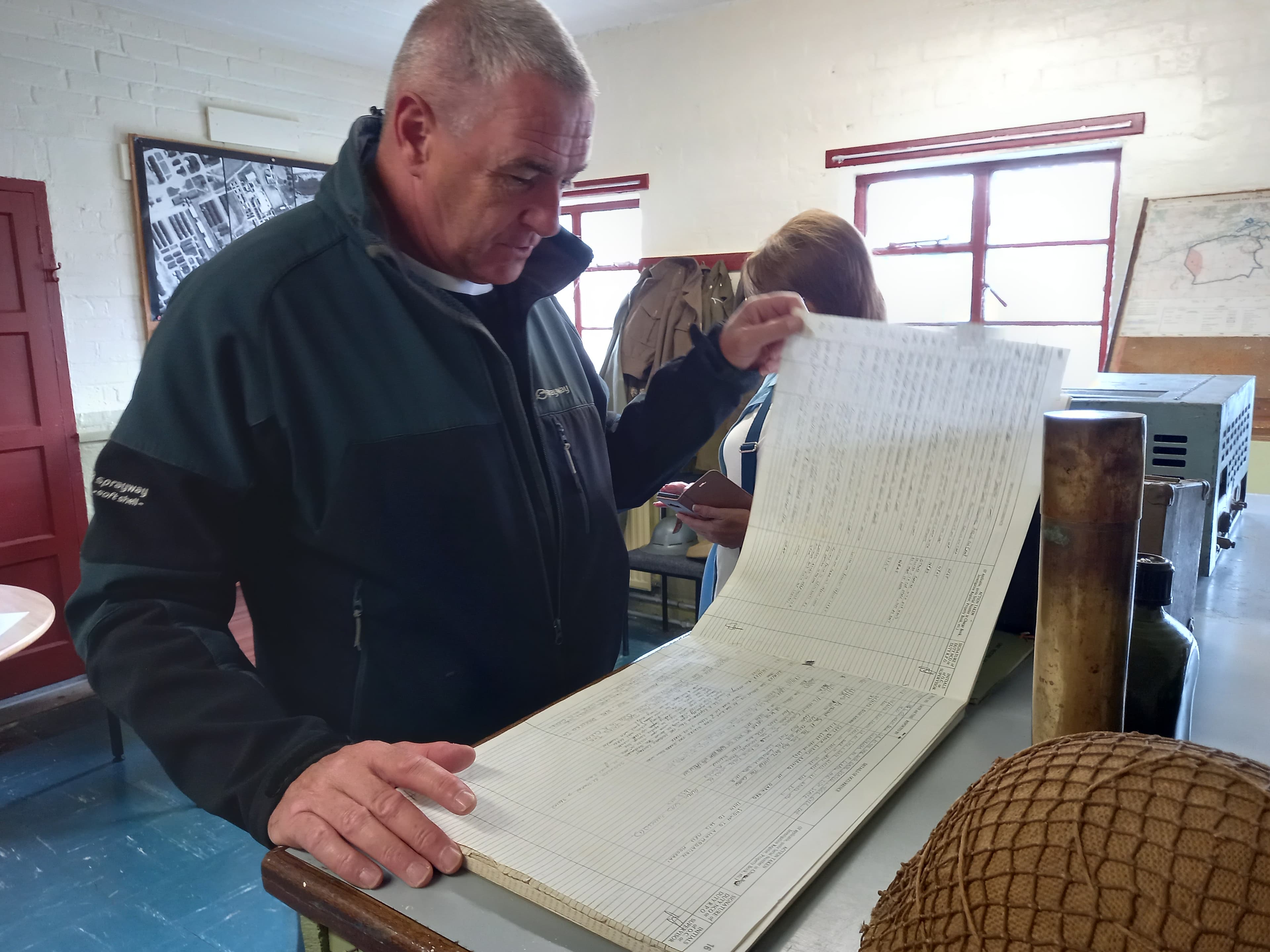 Man examining a wartime ledger in the museum at Cultybraggan Camp